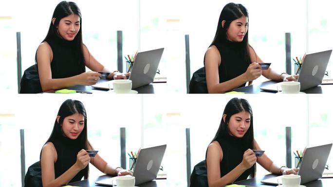 4k镜头亚洲女商人使用信用卡进行在线交易的场景，并在办公场所使用笔记本电脑令人惊讶-办公空间，商务和