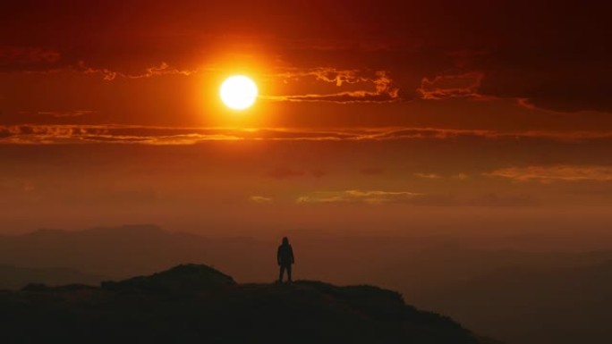 男性站在日出背景的山顶上。时间流逝
