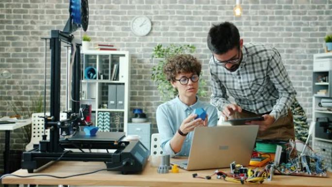 男人和女人在办公室里使用平板电脑、笔记本电脑和3d打印机说话工作