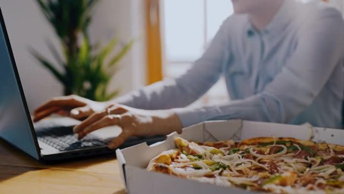 DS女人在家里用笔记本电脑工作时吃披萨