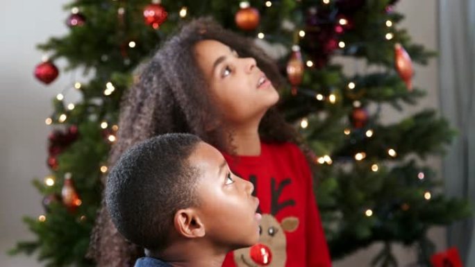 孩子们在背景中观看带有圣诞树的猜字谜游戏