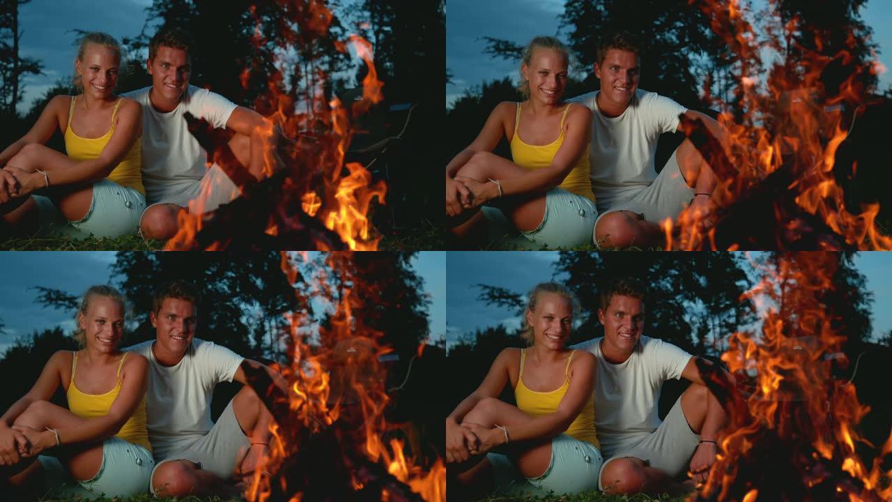 时间重新映射，关闭: 快乐的旅行者夫妇拥抱并看着篝火