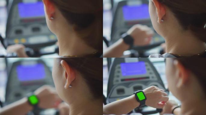 高清慢动作: 女人在健身房锻炼身体，看着智能手表，绿屏