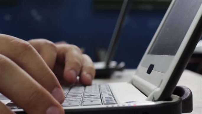 男人用他的笔记本电脑把手放在键盘上。