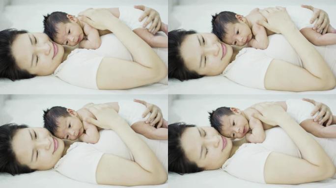 亚洲母亲与刚出生的儿子躺在胸前睡觉