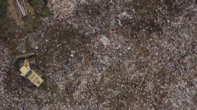 4k直下空中变焦，看到欧洲白鹳在垃圾填埋场清理食物，而推土机，卡车和人们在其中工作