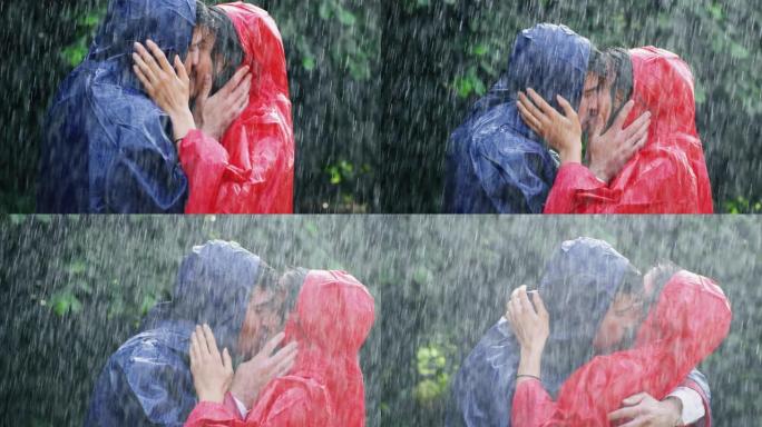 恋爱中的年轻无忧无虑夫妇的慢动作在绿树的背景下在雨中拥抱和亲吻
