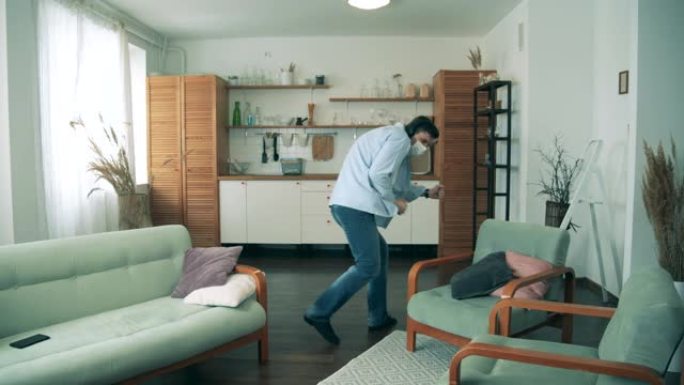 戴着口罩的成年男子正在他的公寓里跳舞。新型冠状病毒肺炎锁定概念。