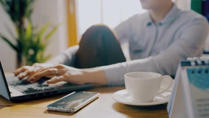 DS女人在家里用笔记本电脑工作时喝杯咖啡