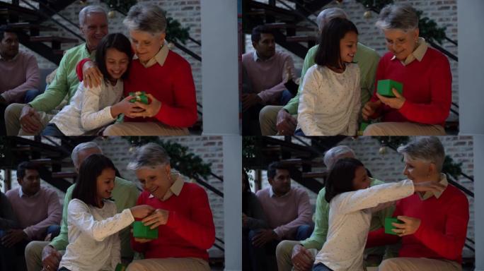 充满爱心的孙女在圣诞节期间拥抱和微笑时将礼物交给祖母