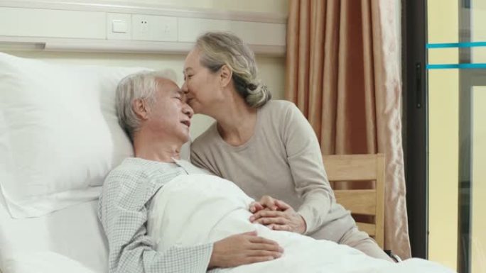 充满爱心的亚洲老年妇女在医院病房探望丈夫