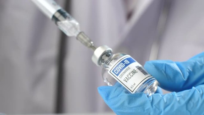 医生进注射器从小瓶被新型冠状病毒肺炎接种给病人在实验室，医用注射器注射疫苗