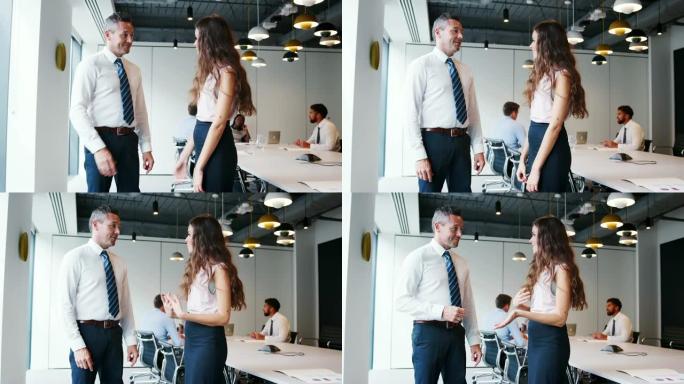 商人和女商人在现代会议室与同事在慢动作背景下在桌子旁开会的同事握手