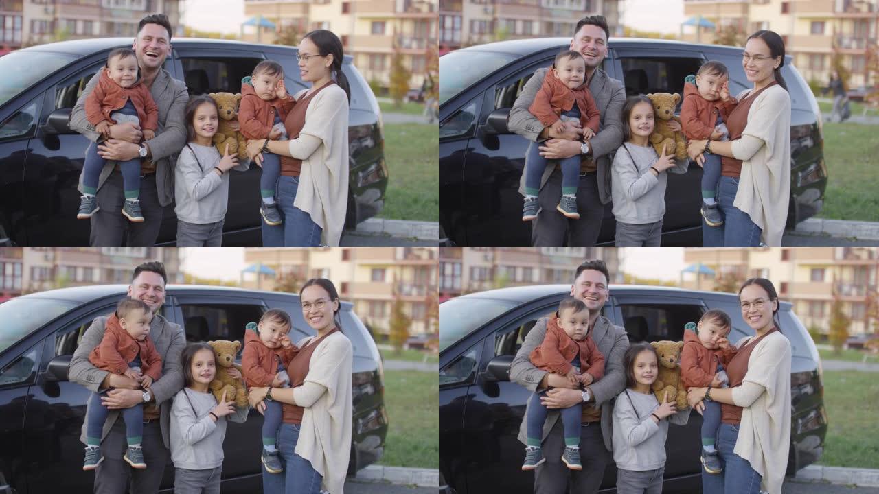 孩子们在汽车前摆姿势的幸福家庭