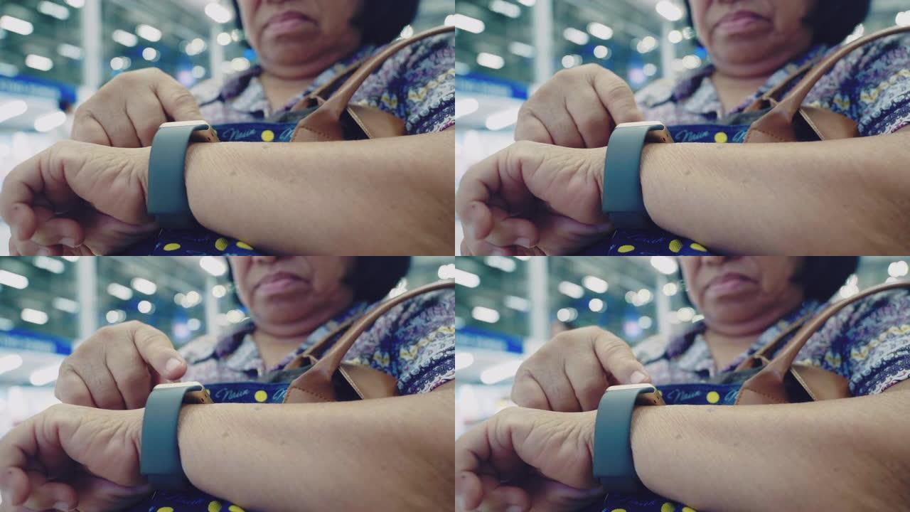 亚洲资深女性在机场使用智能手表