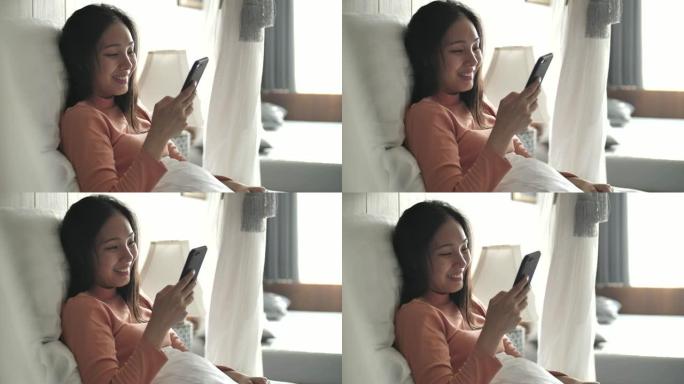 美丽的亚洲女人在家床上使用电话
