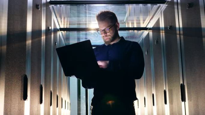 眼镜中的IT支持工程师正在服务器机房中操作笔记本电脑