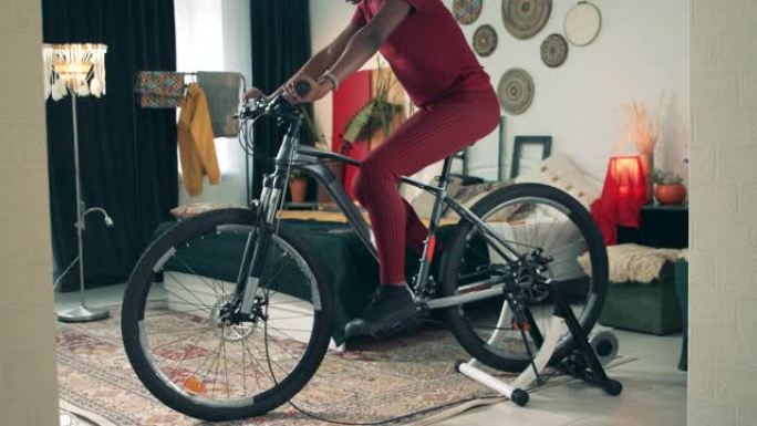 非裔美国女士正在检疫骑自行车。在家运动，在家健身。