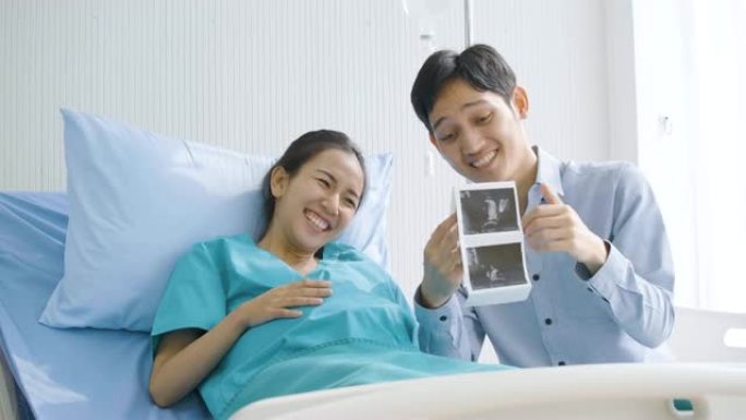 可爱的亚洲夫妇兴奋的准父母看超声波照片。