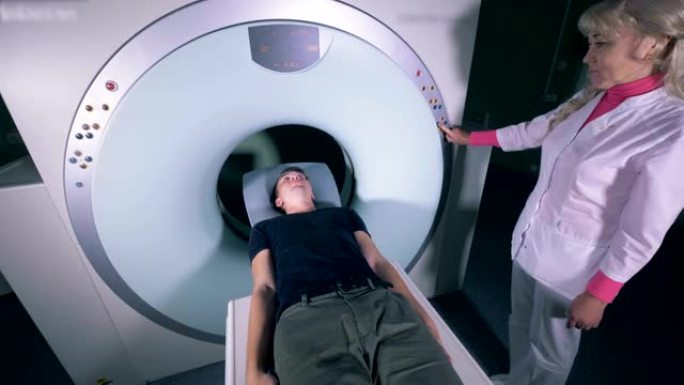 患者在女医生的监督下进入MRI机制