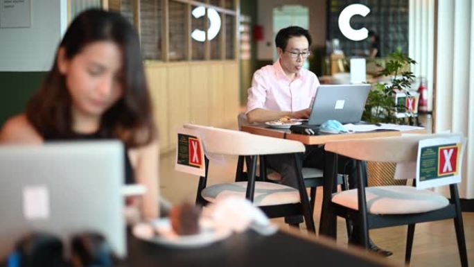 一名在咖啡馆工作的亚裔中国白领使用笔记本电脑