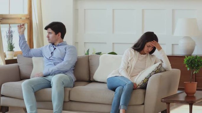 争吵后，沮丧的年轻家庭夫妇分别坐在沙发上