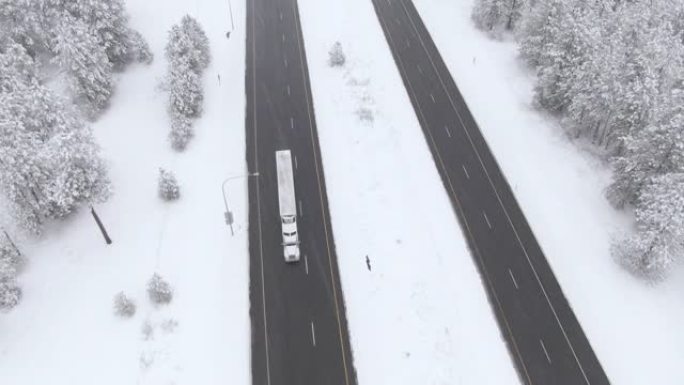 空中: 在暴风雪中沿着湿滑的高速公路飞驰的卡车上方。