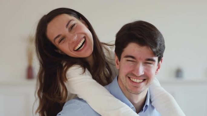 牙齿微笑的年轻夫妇一起笑着看着相机