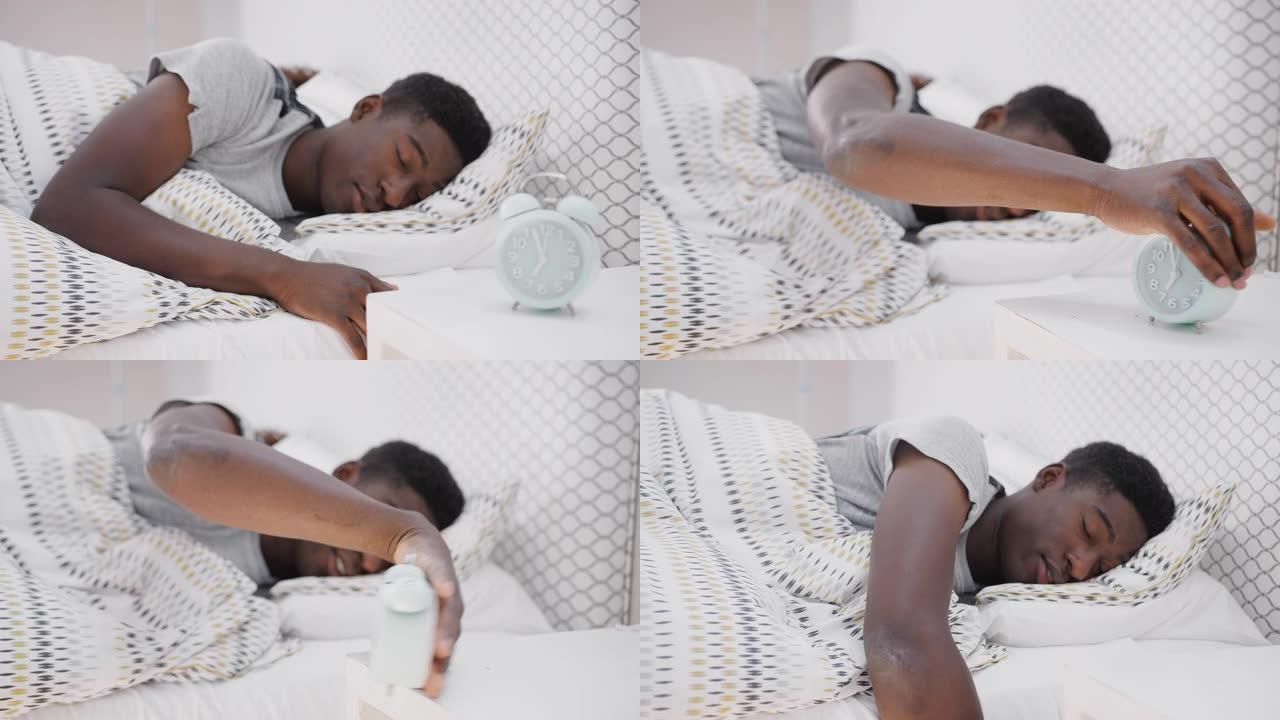在床上睡着的男人伸出手来关闭床头柜上的闹钟