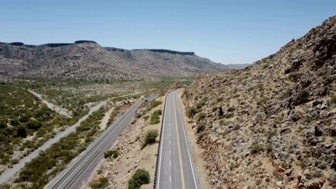 亚利桑那州雄伟的沙漠岩石山路的静态航拍，当汽车经过时，无人机升起。公路旅行概念。