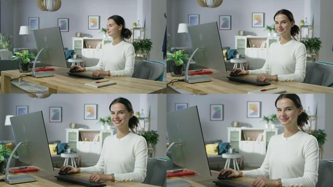缩小美丽的年轻女子在舒适的客厅在个人电脑上工作的肖像照片。她看着镜头迷人地微笑着。