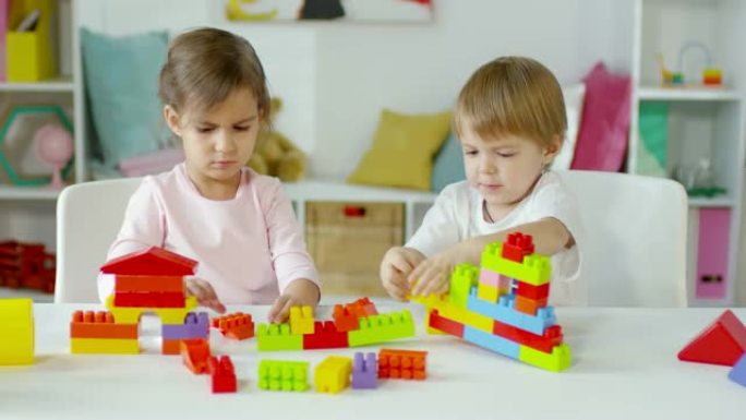 两个孩子坐在桌子旁玩建筑玩具