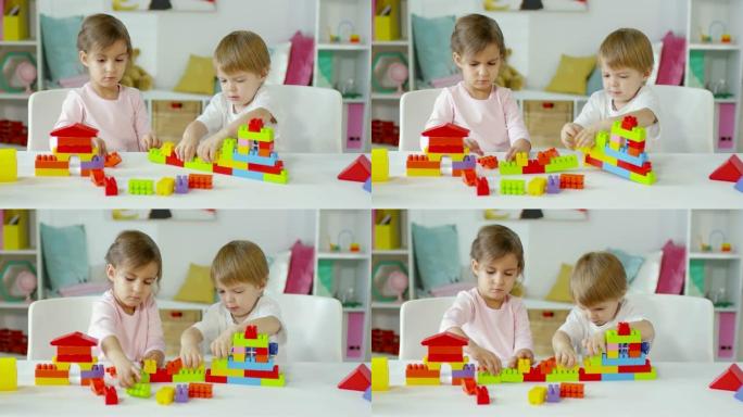 两个孩子坐在桌子旁玩建筑玩具