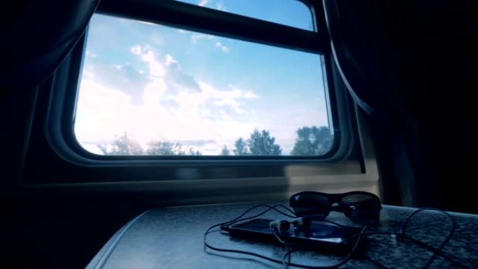 在火车教练的桌子上关闭带有耳机和眼镜的智能手机
