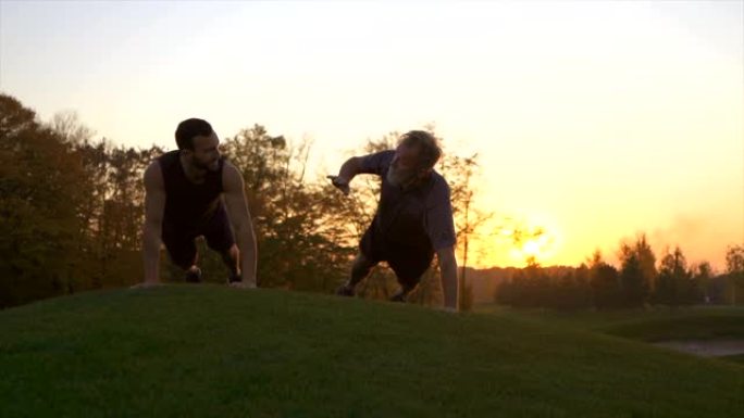 日落背景下的两个人在公园里推着。慢动作