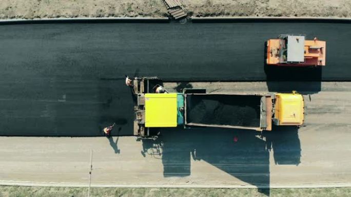 工业工人正在做一条柏油路。道路施工现场的沥青摊铺机。