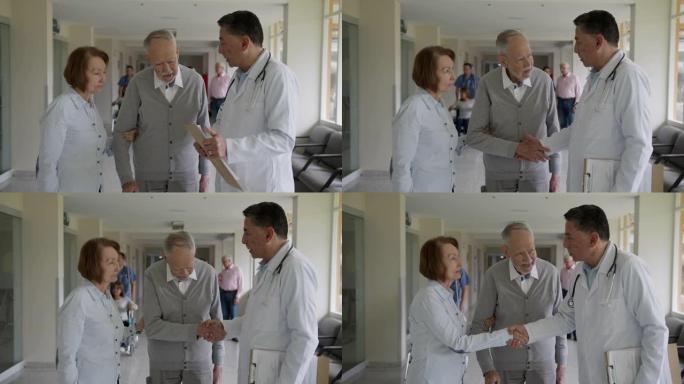 男医生与老年患者交谈，并在医院走廊与他们握手再见