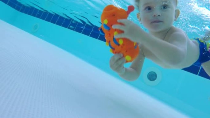 一个男孩在水下游泳，在水下抓住一个玩具，特写镜头。