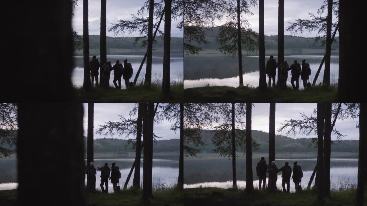 徒步旅行者在晚上讨论美丽的湖泊的剪影