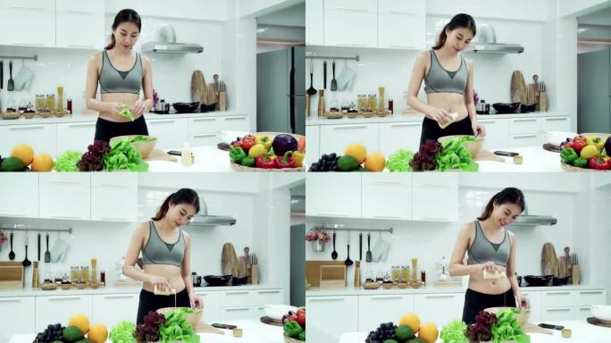 穿着运动服的亚洲女性在周末早上在厨房家里的智能手机上做沙拉和看食谱。健康饮食和健康生活方式理念。