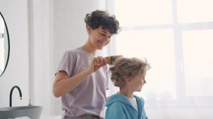 有爱心的父母在家浴室用发刷刷小男孩的头发