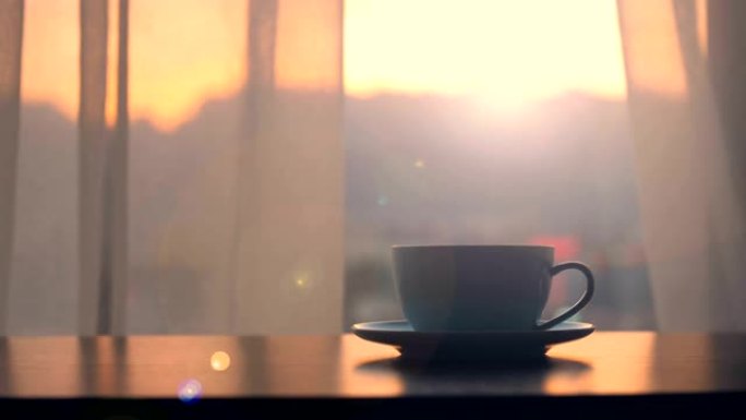 桌子上有日落窗口背景的咖啡杯