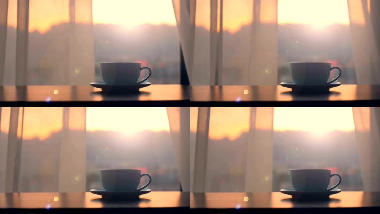 桌子上有日落窗口背景的咖啡杯