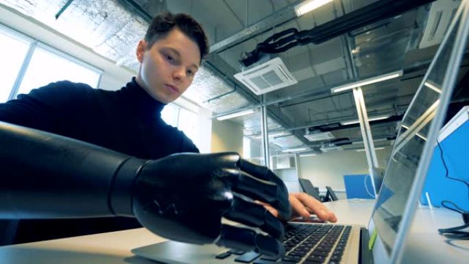人的假肢在笔记本电脑上打字。机器人机器人臂概念。