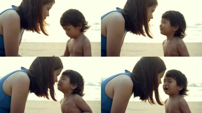 年轻的母亲和小男孩在沙滩上玩沙子