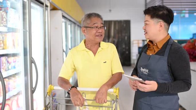 一位亚洲华人高级男子与一位穿着围裙的女店主交谈，询问店员的情况