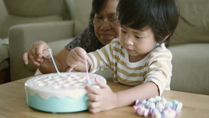 亚洲祖母和孙子在家里玩玩具。