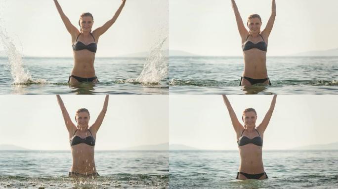 女人在海滩上享受夏天，在空中飞溅海水