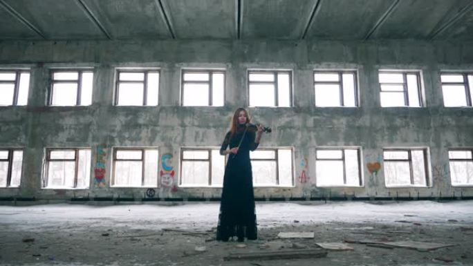 女人站在被毁的建筑里拉小提琴。