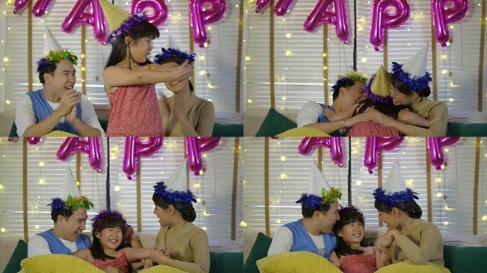 年轻亚洲家庭在家沙发上放松的肖像。父母用爱亲吻他们的女儿。幸福的家庭一起享受时光。